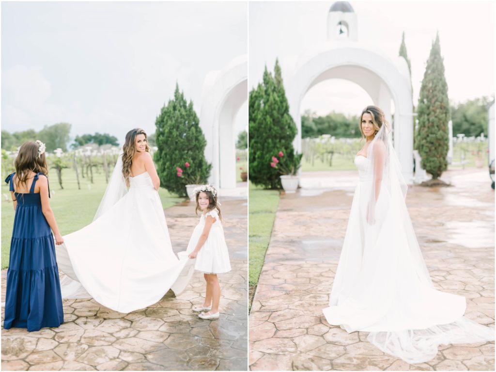 Two daughters of the bride hold her wedding train as their mother smiles back over her shoulder on a cobblestone path at a winery in Houston by Christina Elliott Photography. daughters of the bride daughters holding wedding train cobblestone paths #christinaelliottphotography #christinaelliottweddings #Winerywedding #Houstonweddings #newlyweds #weddingdress #weddingphotography #Houstonweddingphotographers #dreamyweddings #bluesuit #weddingstyle #mrandmrs #weddinggoals #Houstonphotographers