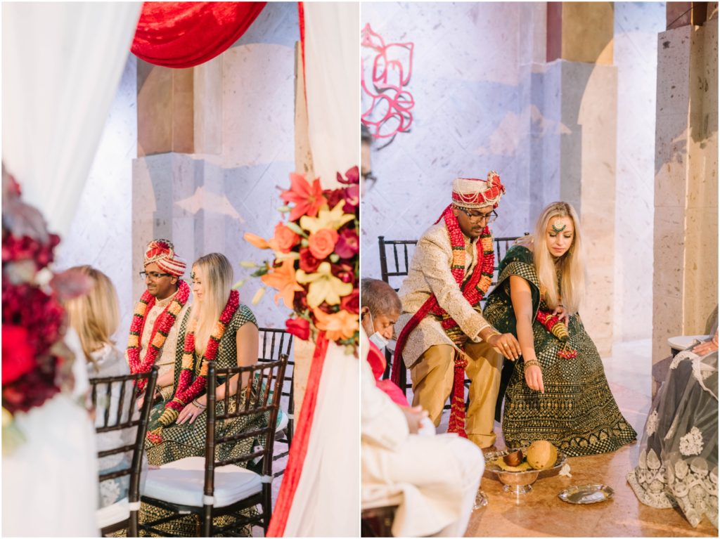 Christina Elliott Photography captures a bride and groom in traditional wedding attire sitting next to one another with red leis around their neck in Houston, Texas. Mixed-cultural marriages united wedding couple #christinaelliottphotography #christinaelliottweddings #thebelltoweron34th #belltowerwedding #houstonweddings #houstonweddingphotographers #mrandmrs #newlymarried #weddinginspiration #bridalgown #groomstyle #texasweddingphotographers #tietheknot #traditionalindianwedding