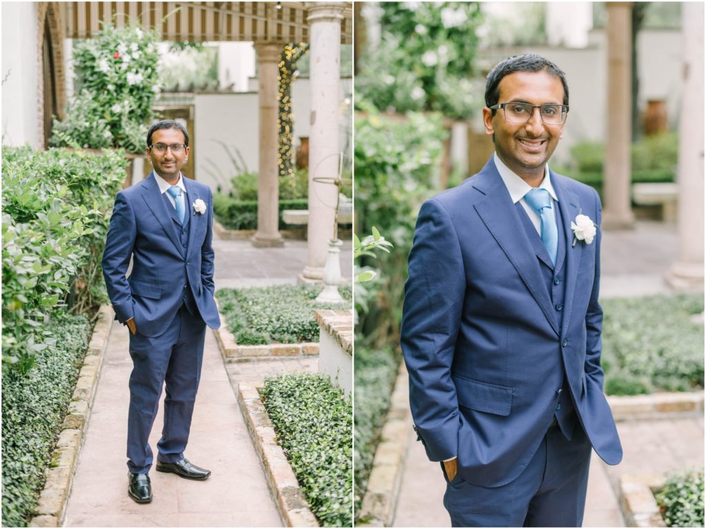 Groom wearing a classic blue suit with light blue tie smiles in the gardens at a Houston wedding venue by Christina Elliott Photography. groom portrait outdoor groom portrait blue suit and tie #christinaelliottphotography #christinaelliottweddings #thebelltoweron34th #belltowerwedding #houstonweddings #houstonweddingphotographers #mrandmrs #newlymarried #weddinginspiration #bridalgown #groomstyle #texasweddingphotographers #tietheknot #traditionalindianwedding