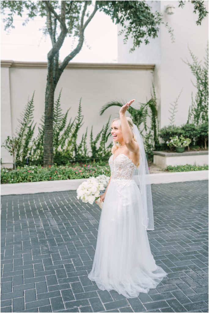 Petite blonde bride cheers in her wedding gown outside Houston wedding venue The Bell Tower on 34th by Christina Elliott Photography. blonde petite bride empire waist wedding dress lace details #christinaelliottphotography #christinaelliottweddings #thebelltoweron34th #belltowerwedding #houstonweddings #houstonweddingphotographers #mrandmrs #newlymarried #weddinginspiration #bridalgown #groomstyle #texasweddingphotographers #tietheknot #traditionalindianwedding