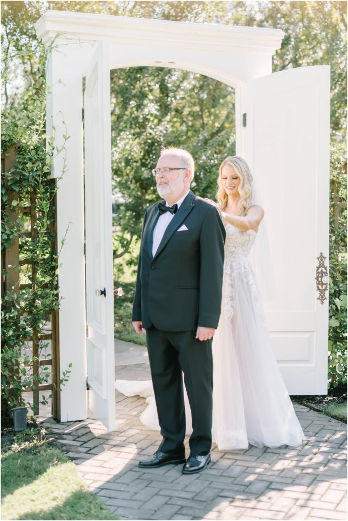 Father of the bride anxiously awaits his first look at this daughter as she taps him on the shoulder by Christina Elliott Photography, a Conroe photographer. father of the bride first look with dad #christinaelliottphotography #christinaelliottweddings #houstontx #houstonweddings #houstonweddingphotographers #carriagehousewedding #conroetexas #texasweddingvenues #carriagehousechapel #cottageweddings #farmhousewedding #sweatheartweddinggown #countrywedding #weddinginspiration