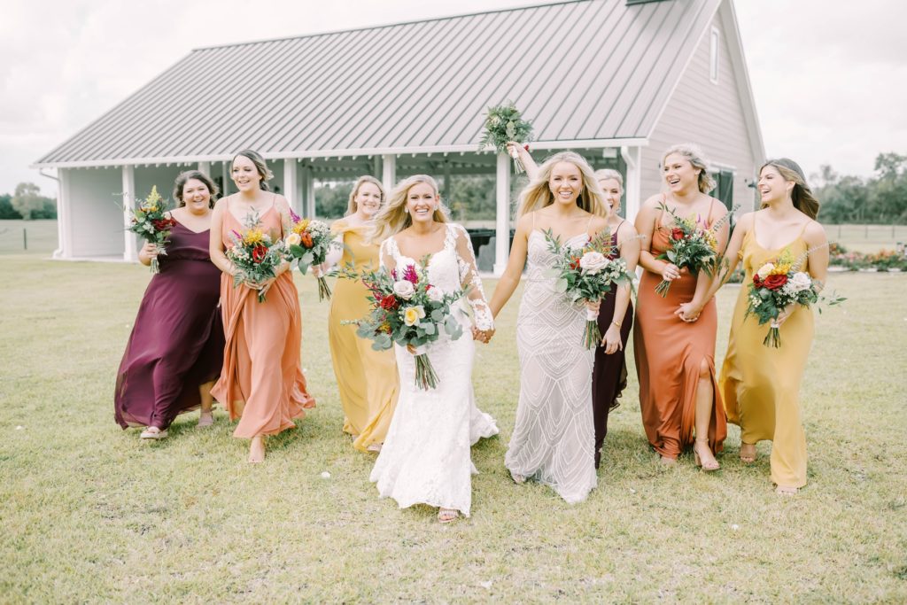 Bride and bridesmaids walk hand in hand while smiling in Texas by Christina Elliott Photography. bridal party pics fall bridal party inspiration country wedding #christinaelliottphotography #texasweddingphotographer #ranchwedding #countrychic