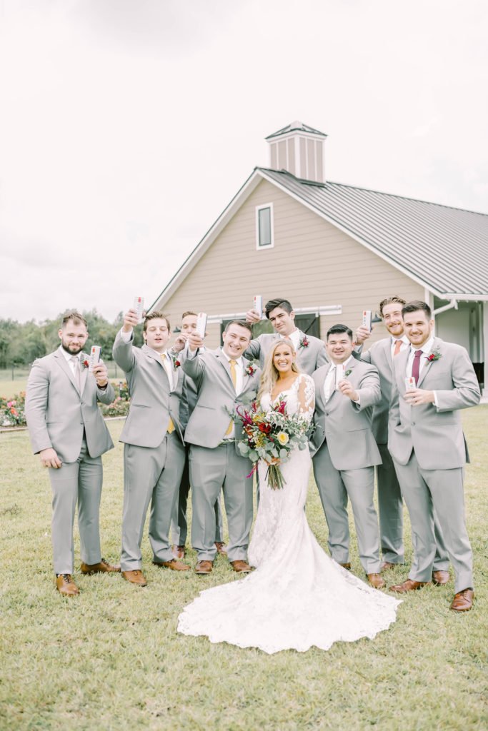 Groomsmen toast their beers as they surround the bride at a wedding in Texas by Christina Elliott Photography. groomsmen toast with bride Texas weddings #christinaelliottphotography #texasweddingphotographer #ranchwedding #countrychic
