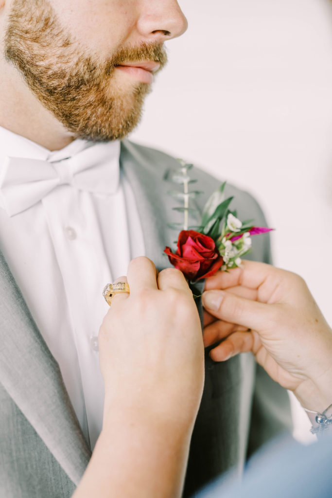 Mother of the groom pins red rose boutonieer on the groom by Christina Elliott Photography a Texas wedding photographer. pin on the flowers mother of the groom #christinaelliottphotography #texasweddingphotographer #ranchwedding #countrychic