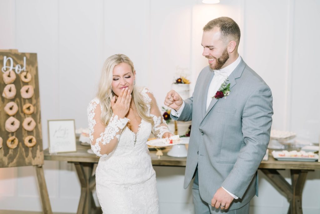 In Texas, Christina Elliott Photography captures a groom feeding the bride cake with a fork as she laughs. wedding cake eating polite cake eating wedding traditions #christinaelliottphotography #texasweddingphotographer #ranchwedding #countrychic