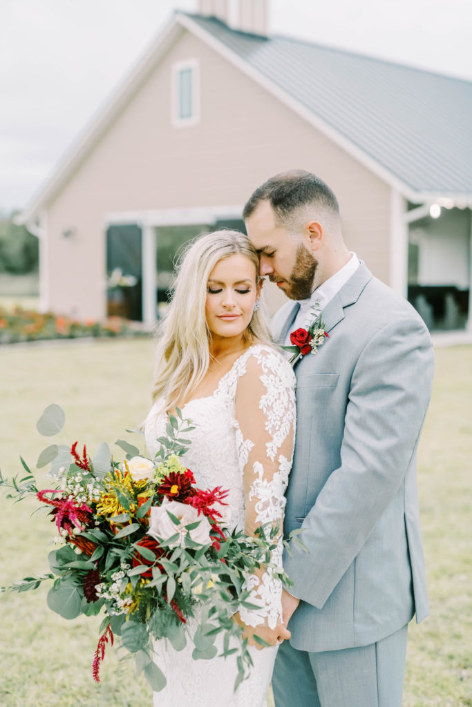 Long sleeve mermaid wedding dress is worn by the bride while leaning into the groom's embrace by Christina Elliott Photography. bride and groom pose Texas wedding style #christinaelliottphotography #texasweddingphotographer #ranchwedding #countrychic