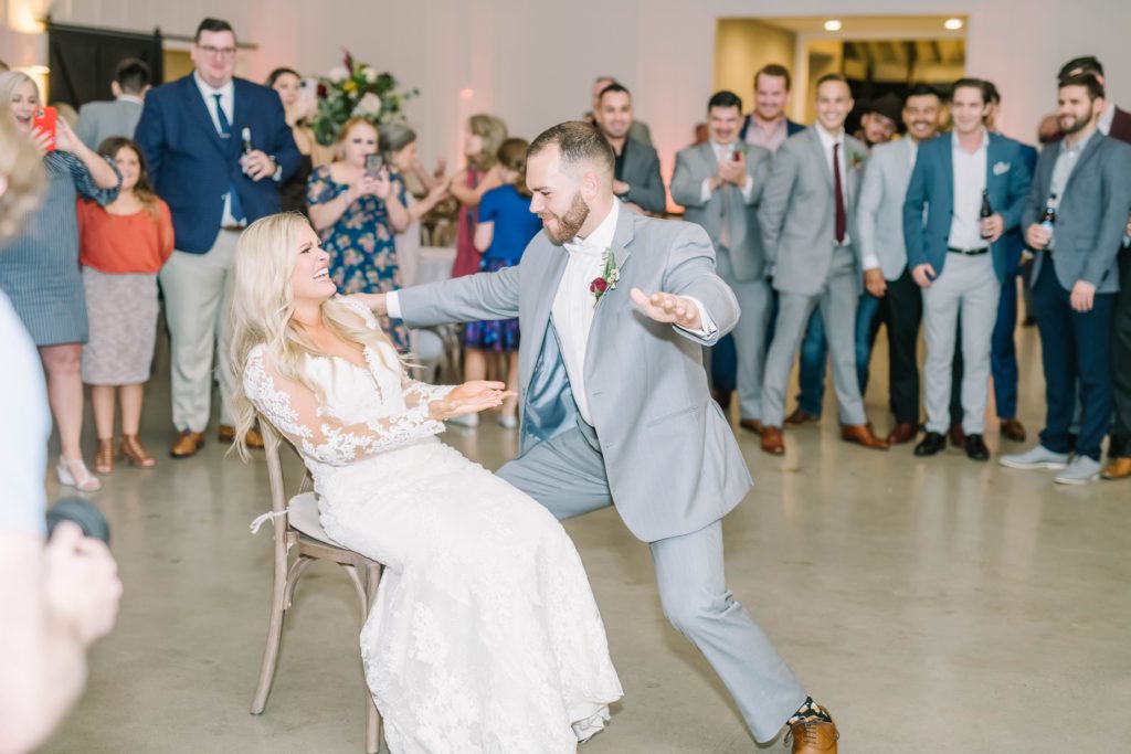 Groom dances for the bride as he goes in to get the garter by Christina Elliott Photography. garter dance groom gets garter reception fun Still Waters Ranch Texas #christinaelliottphotography #texasweddingphotographer #ranchwedding #countrychic