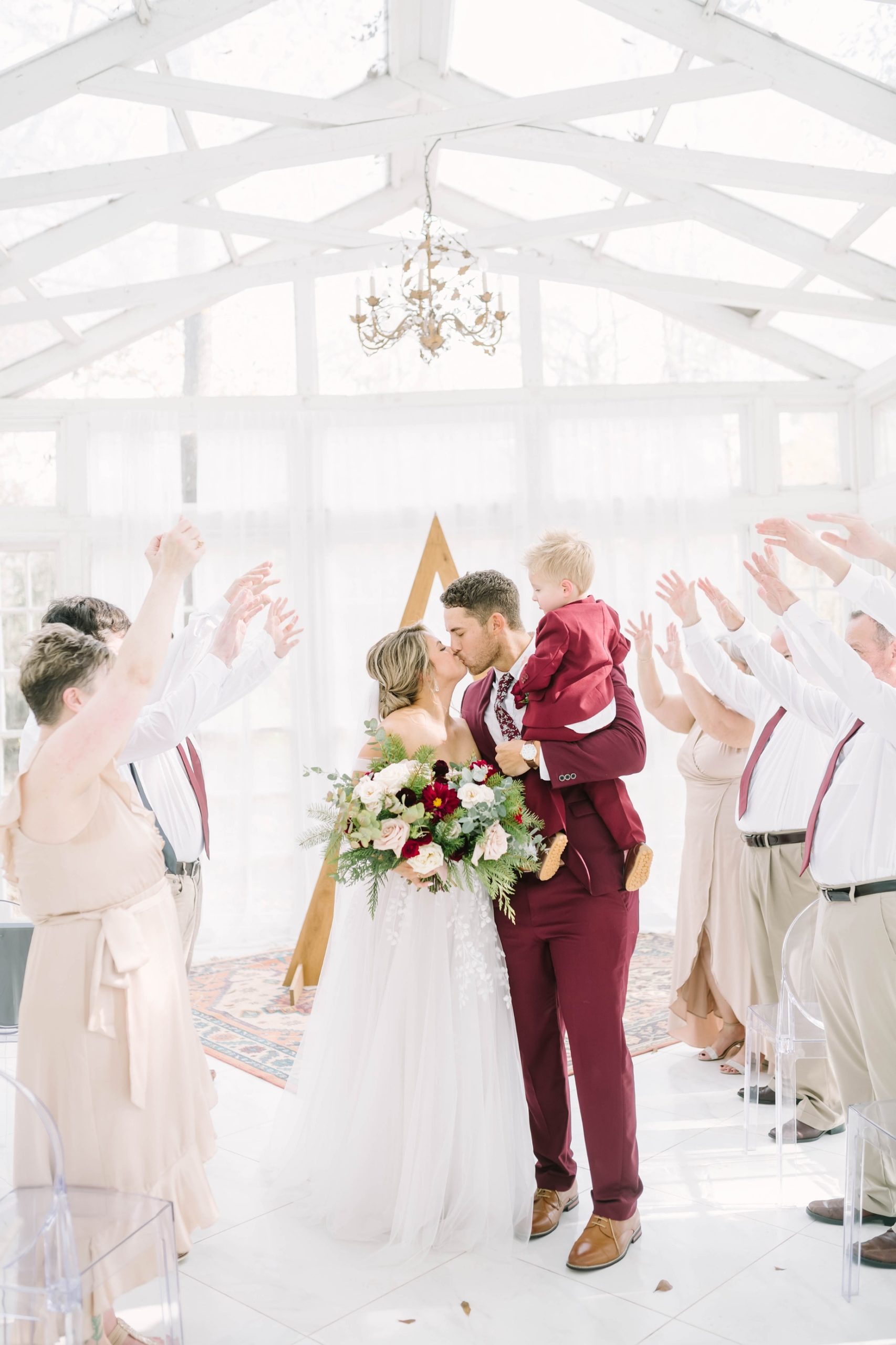 Christina Elliott Photography captures a new bride and groom kissing while family and friends cheer. family and friends cheer for new couple #christinaelliottphotography #theoakatelierwedding #Houstonwinterweddings #weddingphotographersHouston