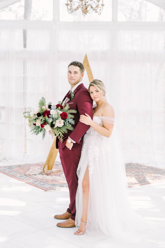 Bride with a leg slit and off-the-shoulder dress holds onto groom's arm by Christina Elliott Photography. winter wedding style for Houston area #christinaelliottphotography #theoakatelierwedding #Houstonwinterweddings #weddingphotographersHouston