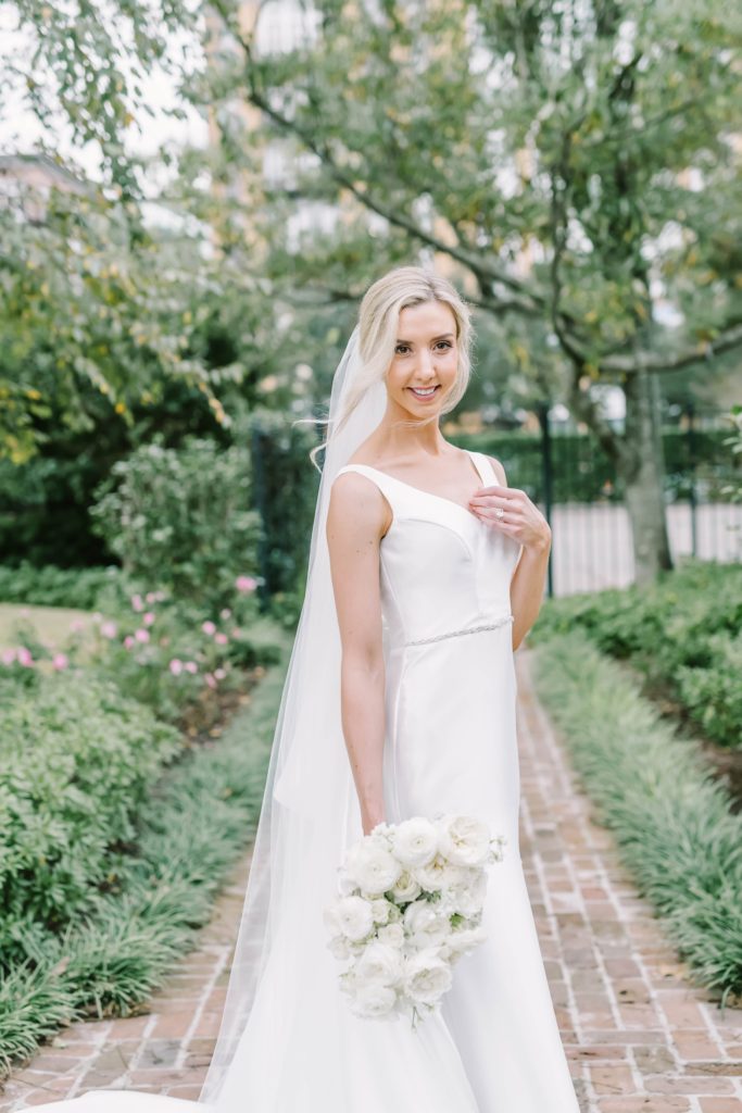In the middle of the River Oaks Garden Club in Houston, a bride poses by Christina Elliott Photography. mermaid gown Houston wedding photographers #christinaelliottphotography #houstonweddings #riveroaksgardenclub #outdoorbridals #houstonbridals