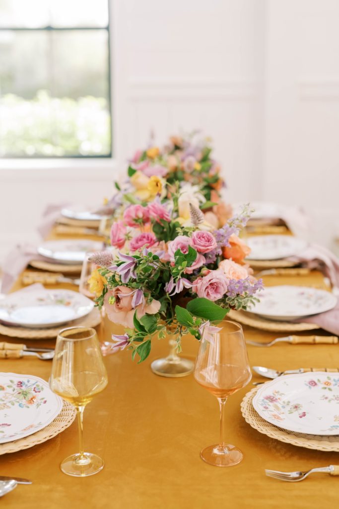 Detailed french country wedding table with floral plates and peach glass goblets by Christina Elliott Photography. french country wed #christinaelliottphotography #Houstonweddings #arrowheadhill #weddingphotographersHouston #springwedding #sayIdo