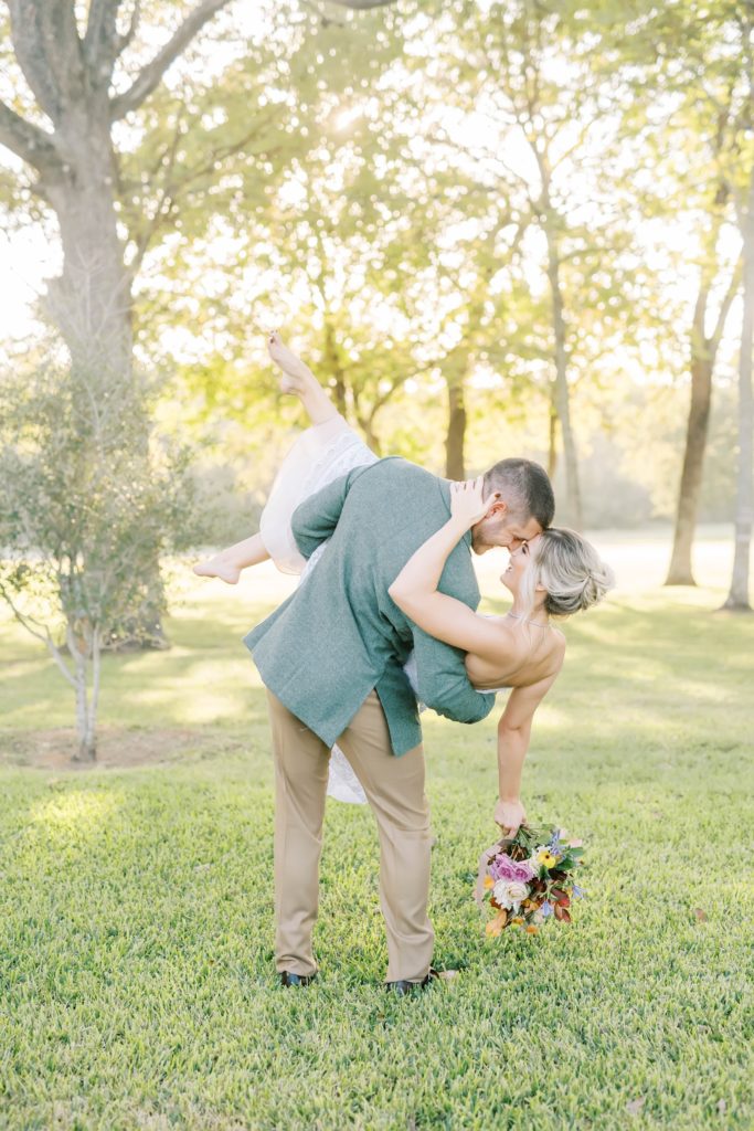 A groom dips his bride while holding her in his arms captured by Christina Elliott Photography of the Houston area. couple dipping pic #christinaelliottphotography #Houstonweddings #arrowheadhill #weddingphotographersHouston #springwedding #sayIdo