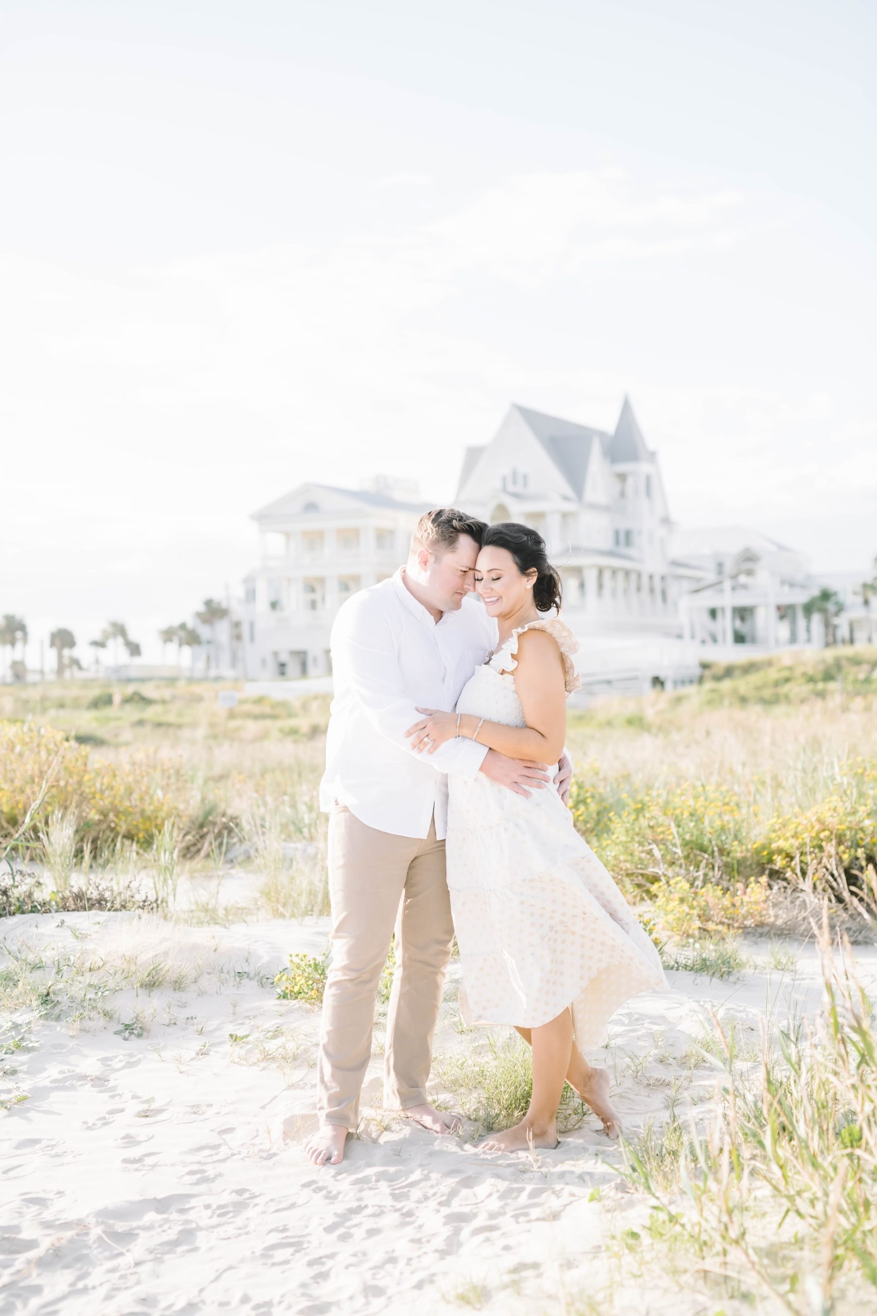 A husband snuggles into his pregnant wife on a white sand beach in Galveston by Christina Elliott Photography. husband snuggles wife #ChristinaElliottPhotography #ChristinaElliottMaternity #Galvestonmaternityphotographers #maternityportraits