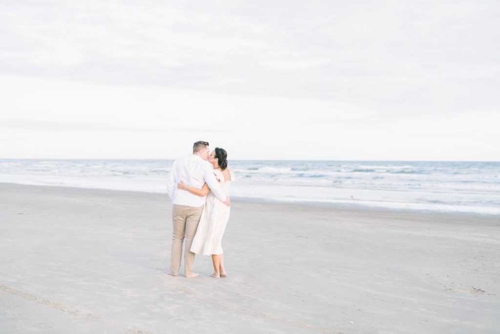 Soon-to-be parents kiss on the beach during a maternity session with Christina Elliott Photography. beach maternity shoots happy couple #ChristinaElliottPhotography #ChristinaElliottMaternity #Galvestonmaternityphotographers #maternityportraits