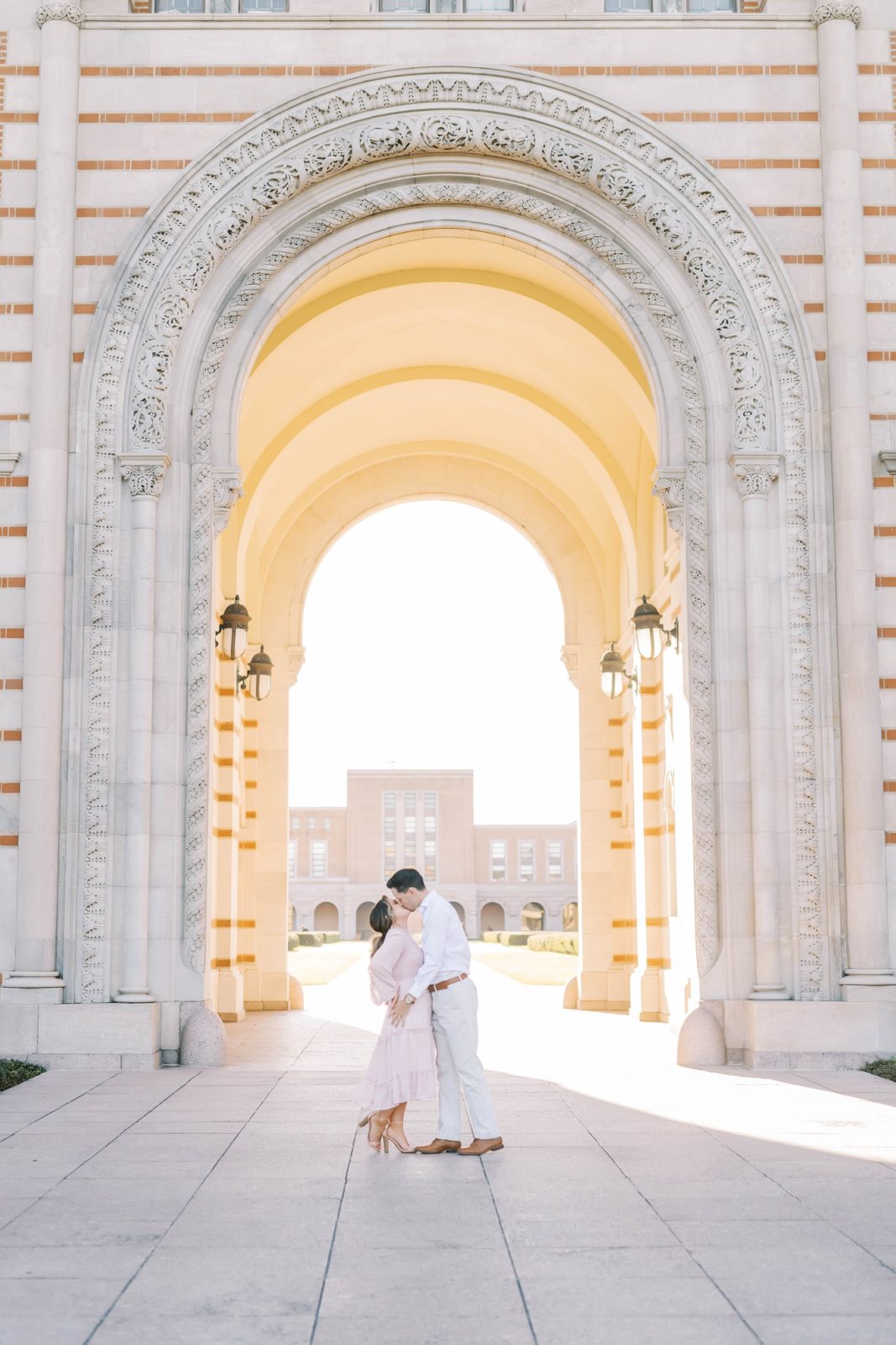 Under stone archways at Rice University a couple kisses by Christina Elliott Photography. engagement locations in Houston #christinaelliottphotography #Houstonengagements #riceuniversity #springengagements #sayIdo #Houstonengagementphotographers