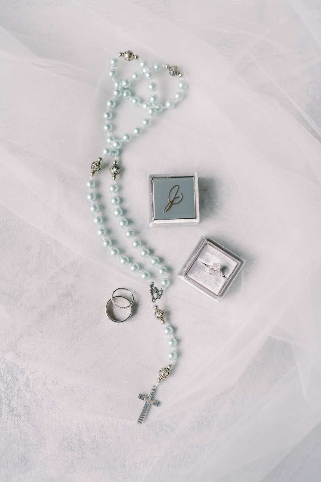 Light blue pearl cross necklace and wedding rings by Christina Elliott Photography in Houston. Wedding ring flat lay cross necklace #christinaelliottphotography #Houstonweddings #catholicchurchweddings #navyblue #sayIdo #Houstonweddingphotographers
