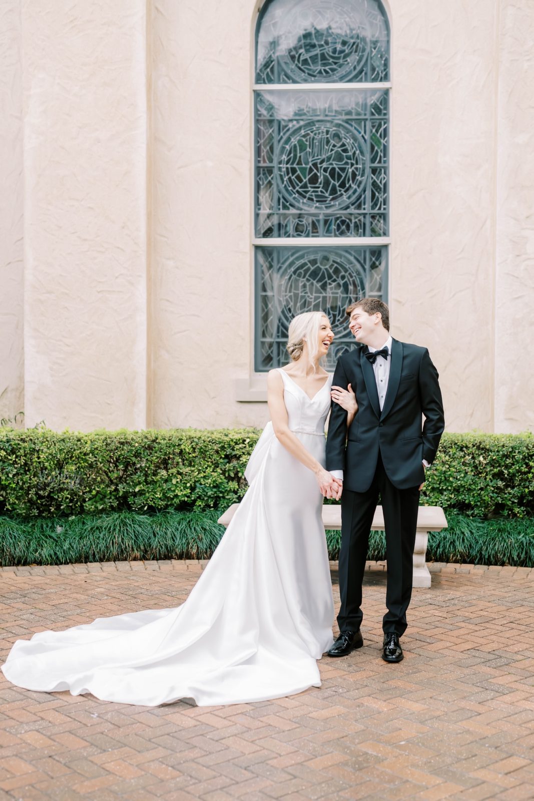 The bride and groom look at one another and laugh outside the glass window by Christina Elliott Photography. laughing newlyweds #christinaelliottphotography #Houstonweddings #catholicchurchweddings #navyblue #sayIdo #Houstonweddingphotographers