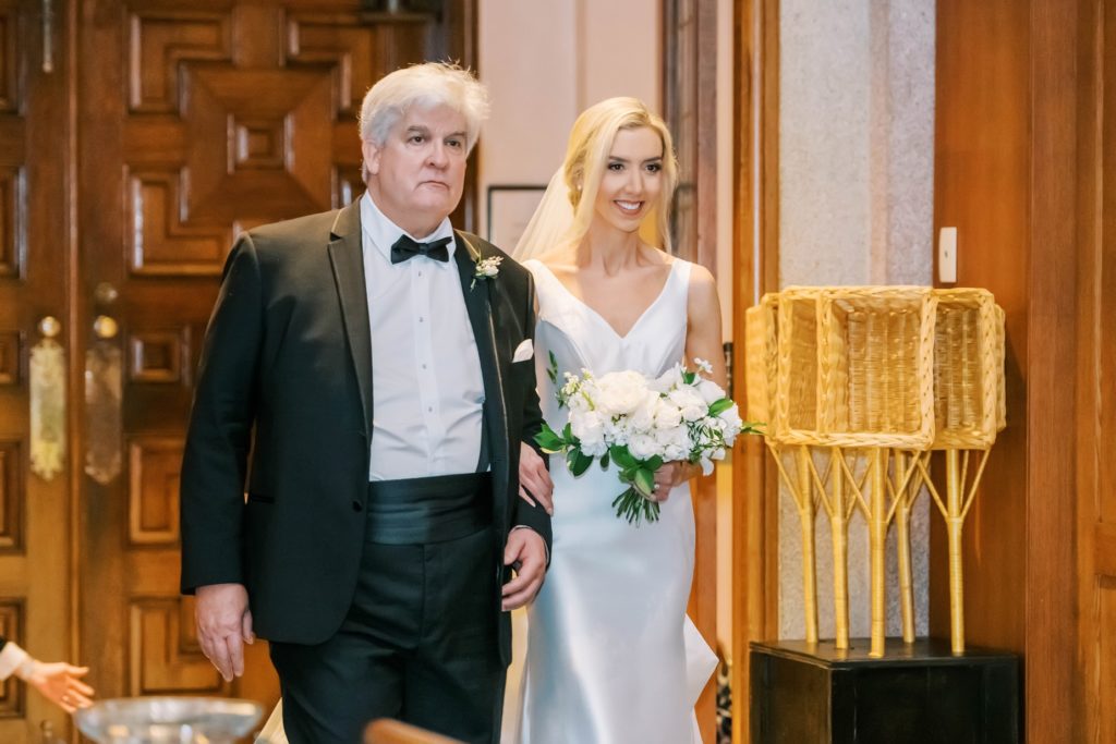 Bride walking down the aisle escorted by her father by Christina Elliott Photography. bride and father down the aisle church wedding #christinaelliottphotography #Houstonweddings #catholicchurchweddings #navyblue #sayIdo #Houstonweddingphotographers