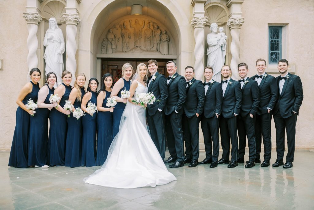 Bride and groom with bridesmaids and groomsmen outside the chapel by Christina Elliott Photography. groomsmen and bridesmaids #christinaelliottphotography #Houstonweddings #catholicchurchweddings #navyblue #sayIdo #Houstonweddingphotographers