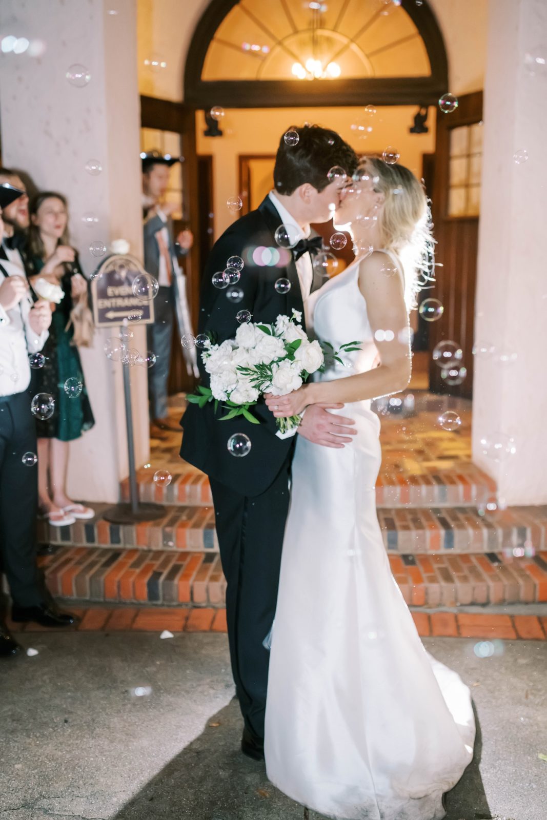 Newlyweds kiss during a fun bubble send off by Christina Elliott Photography in Houston. Bubble send off creative wed send off #christinaelliottphotography #Houstonweddings #catholicchurchweddings #navyblue #sayIdo #Houstonweddingphotographers