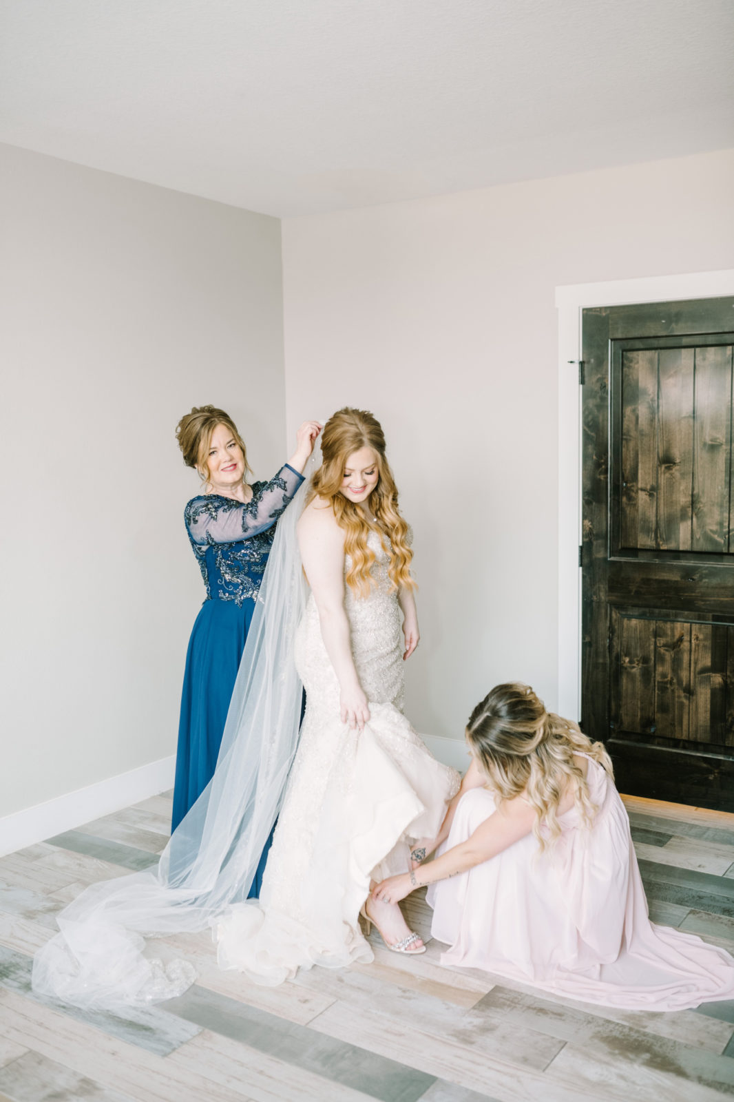 A maid-of-honor helps the bride put on her heels for her wedding by Christa Elliott Photography. bride getting ready #ChristinaElliottPhotography #ChristinaElliottWeddings #StillWatersRanchWedding #Texasweddings #countrywedding #ranchwedding