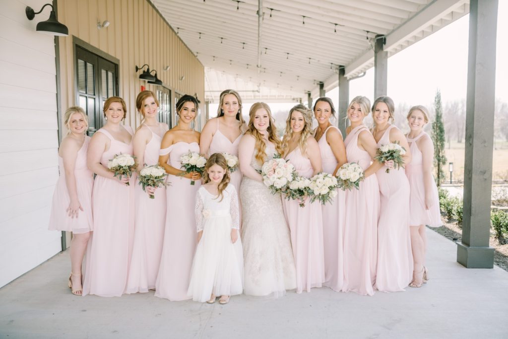 A bride with all her bridesmaids and flower girl on a porch in Texas by Christina Elliott Photography. porch wedding portrait #ChristinaElliottPhotography #ChristinaElliottWeddings #StillWatersRanchWedding #Texasweddings #countrywedding #ranchwedding