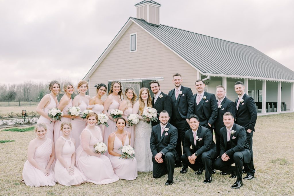 Bridal party smile outside wedding venue in Texas with the bride and groom by Christina Elliott Photography. bridal party #ChristinaElliottPhotography #ChristinaElliottWeddings #StillWatersRanchWedding #Texasweddings #countrywedding #ranchwedding