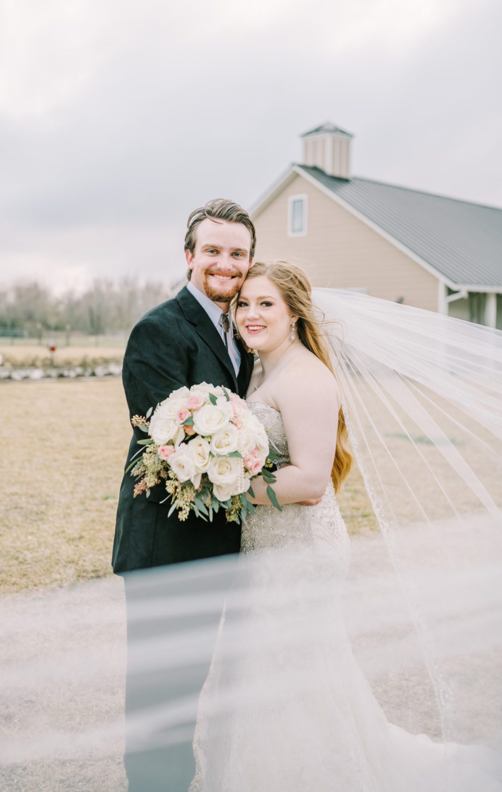 Sheer veil blowing in the wind in front of the bride and groom by Christina Elliott Photography. sheer veil blowing in wind #ChristinaElliottPhotography #ChristinaElliottWeddings #StillWatersRanchWedding #Texasweddings #countrywedding #ranchwedding