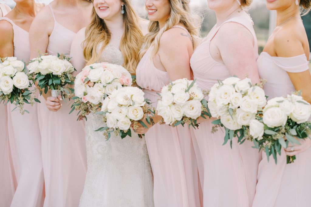 Christina Elliott Photography captures a detailed wedding shot of bridesmaids holding bouquets. bridesmaid bouquet pink dress #ChristinaElliottPhotography #ChristinaElliottWeddings #StillWatersRanchWedding #Texasweddings #countrywedding #ranchwedding