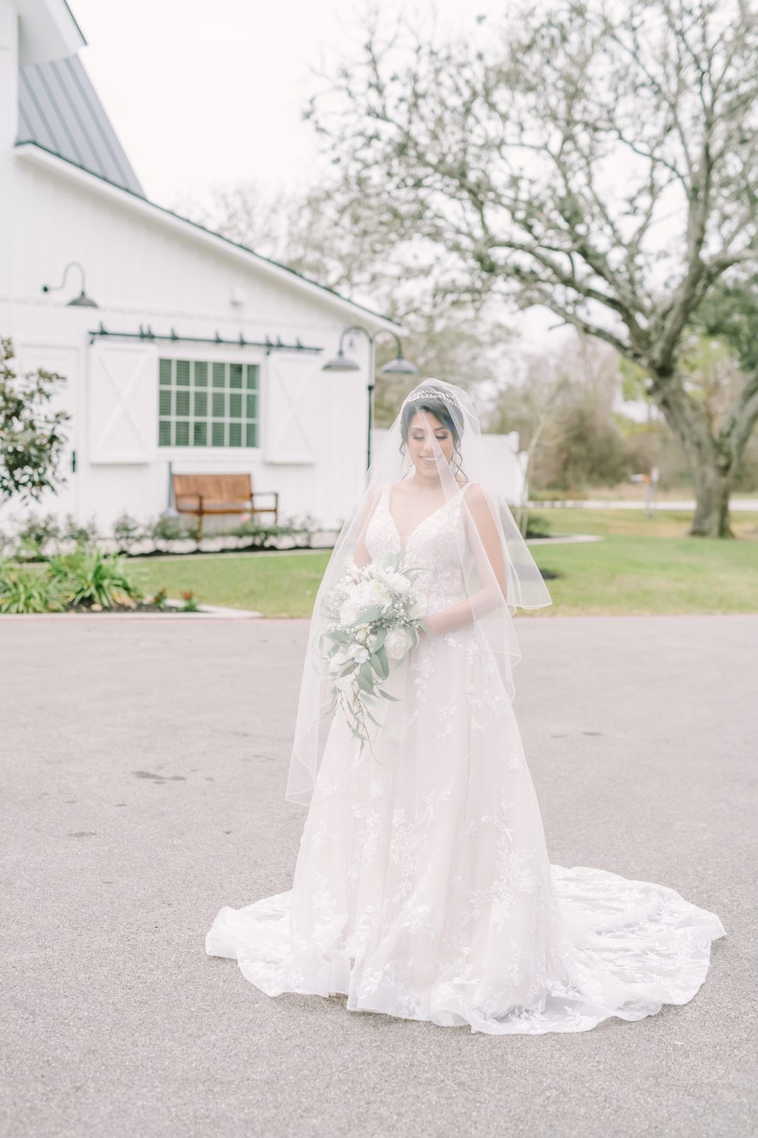 Bride with a veil over her face smiling at The Springs Farmhouse by Chrsitna Elliott Photography. veil lace gown bridal #ChristinaElliottPhotography #ChristinaElliottBridals #Houstonweddings #Farmhousewedding #TheSpringsVenue #BridalsHouston