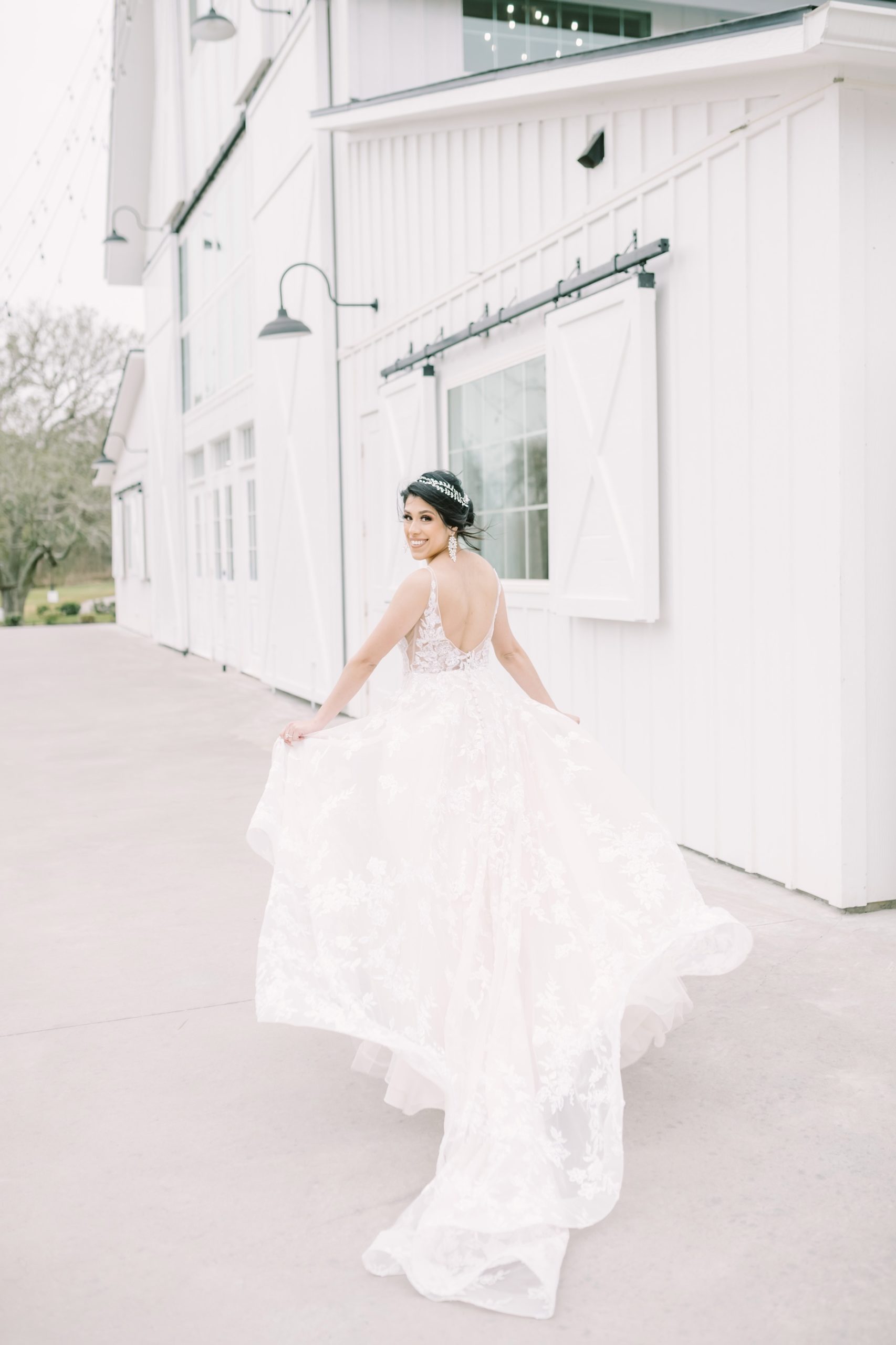 With her dress billowing in the wind a bride runs toward a barn captured by Christina Elliott Photography. yes to the dress #ChristinaElliottPhotography #ChristinaElliottBridals #Houstonweddings #Farmhousewedding #TheSpringsVenue #BridalsHouston