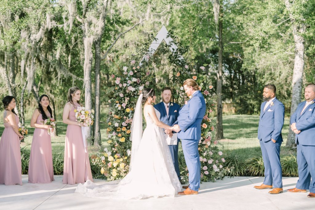 Bride and groom illuminated by the sunshine while standing at the altar by Christina Elliott Photography. floral altar green wedding #ChristinaElliottPhotography #ChristinaElliottWeddings #Houstonwedding #TheSpringsVenue #EastHoustonweddings #sayIdo