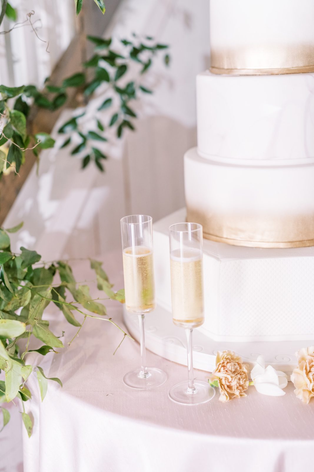 Gold brushed wedding cake with two tall glasses of champagne next to the cake by Christina Elliott Photography. champagne and cake #ChristinaElliottPhotography #ChristinaElliottWeddings #Houstonwedding #TheSpringsVenue #EastHoustonweddings