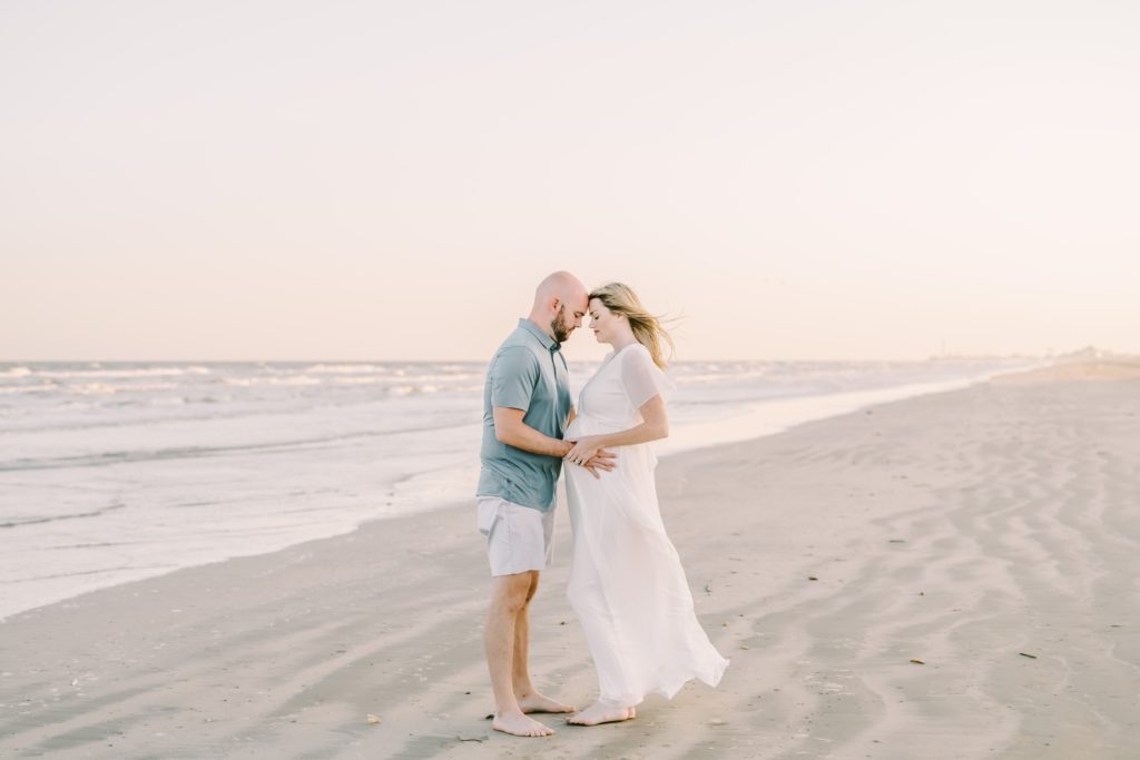 Married couple place hands on pregnant belly captured by Christina Elliott Photography. Galveston maternity photog #ChristinaElliottPhotography #ChristinaElliottFamilies #GalvestonPhotography #Beachmaternityphotography #Texasfamilyphotographers