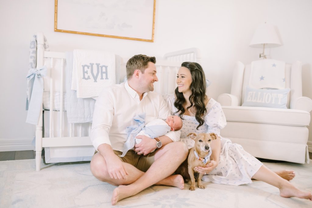 Houston family photographer captures a new family sitting on a nursery floor smiling at one another by Christina Elliott Photography. doggy #ChristinaElliottPhotography #ChristinaElliottNewborns #HoustonLifestyleNewborns #HoustonFamilyPhotographer