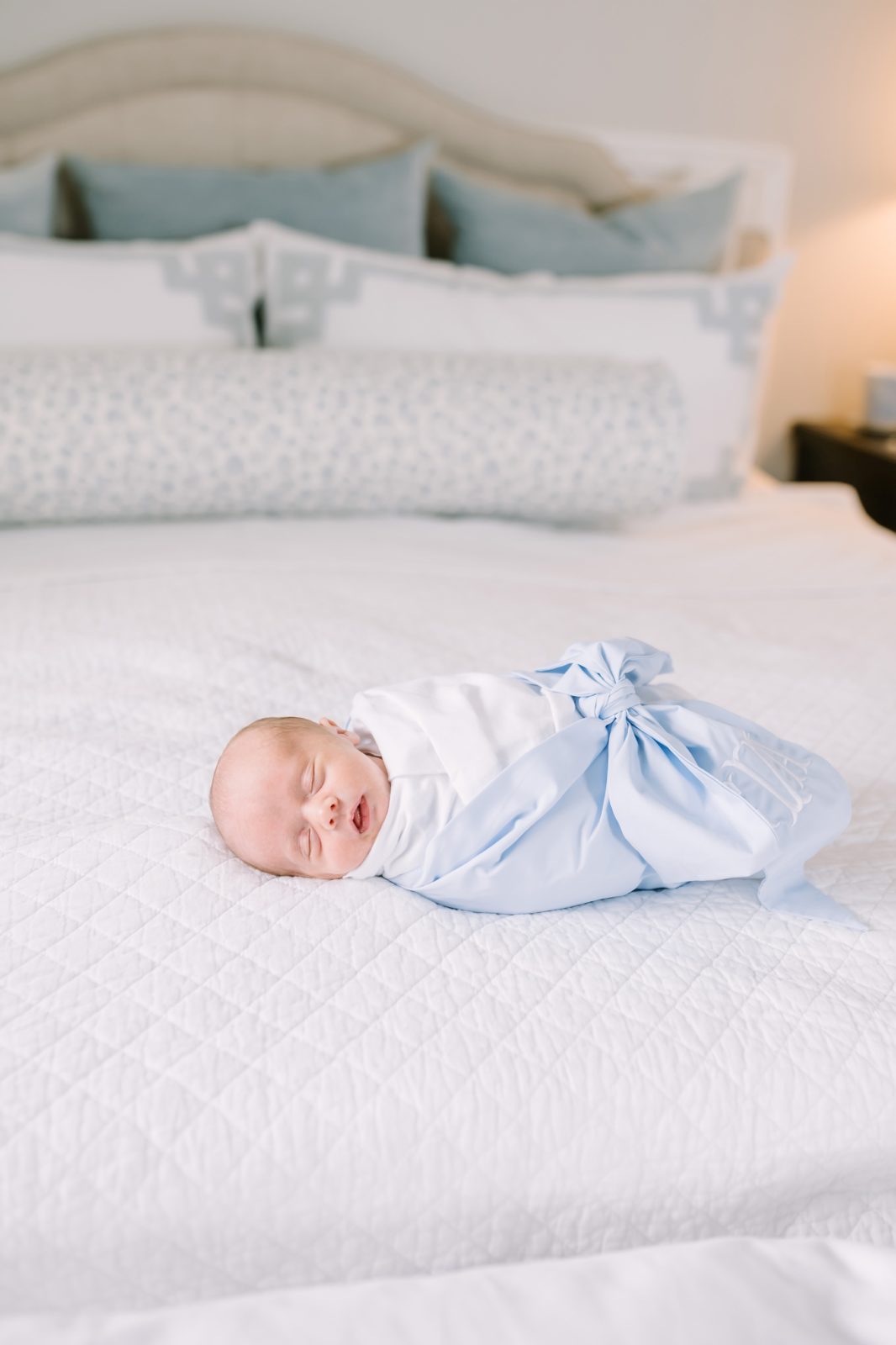 Baby boy swaddled in a blue bow on a bed by Christina Elliott Photography in Houston, Texas. Houston newborn blue bow baby swaddle #ChristinaElliottPhotography #ChristinaElliottNewborns #HoustonLifestyleNewborns #HoustonFamilyPhotographer