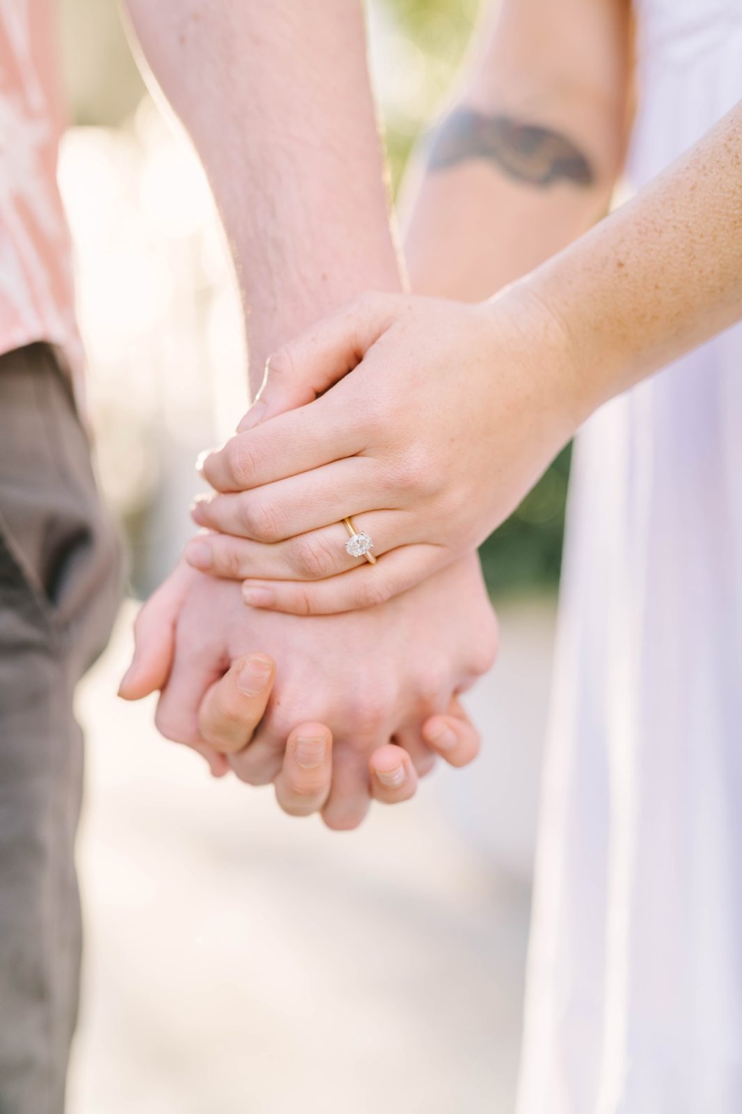 Detailed portrait of a man and woman holding hands wearing gold wedding rings by Christina Elliott Photography. gold ring with oval diamond #ChristinaElliottPhotography #ChristinaElliottEngagements #TheTremontHouse #Texasengagements #shesaidyes