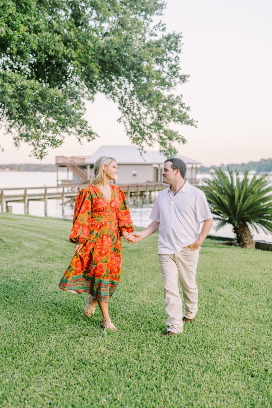 With Lake Livingston behind them, an engaged couple walks while looking adoringly at one another by Christina Elliott Photography. lake love #ChristinaElliottPhotography #ChristinaElliottEngagements #LakeLivingston #summerengagements #Texasphotographer