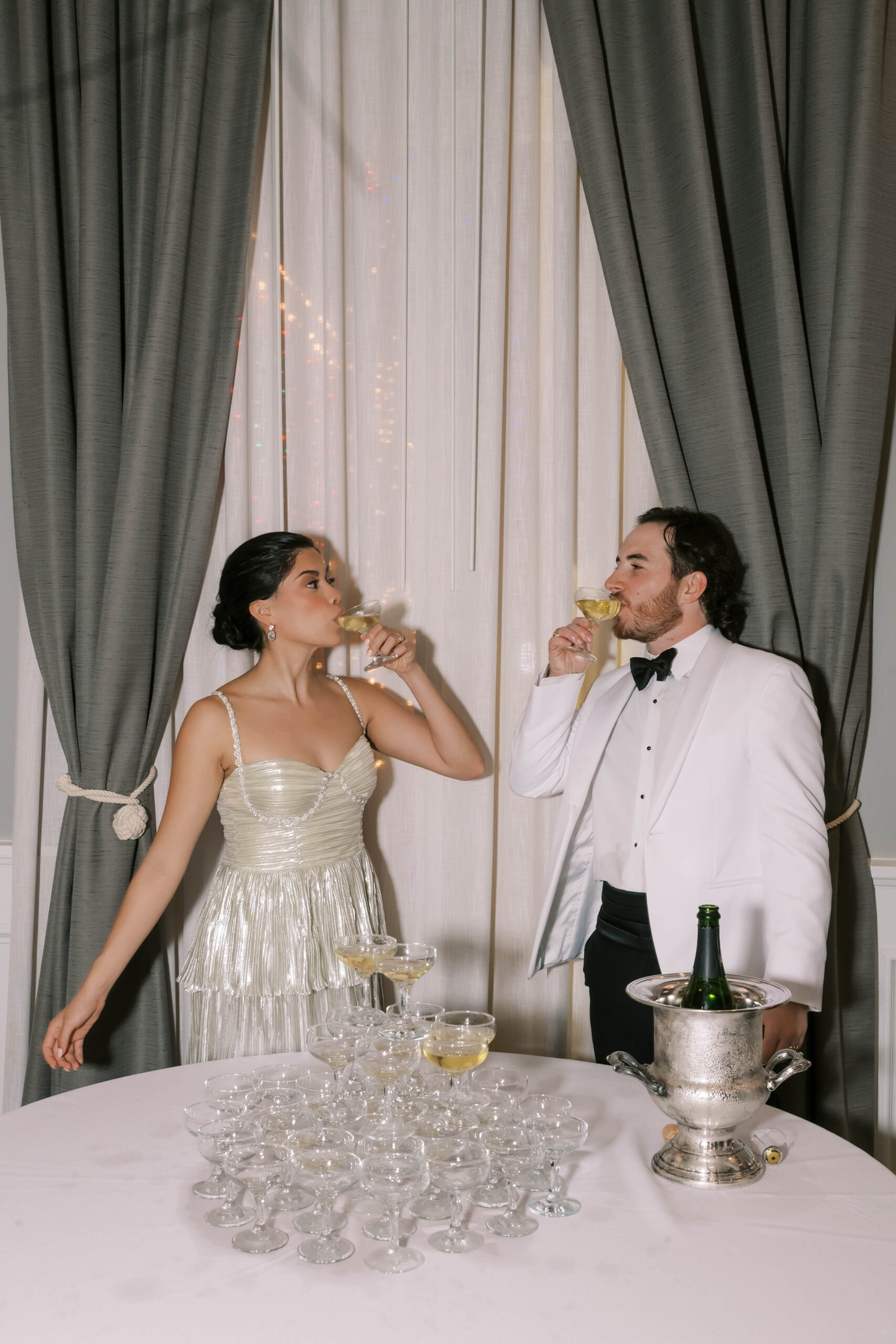 Couple sips Champagne in a chic white suit and gold dress.